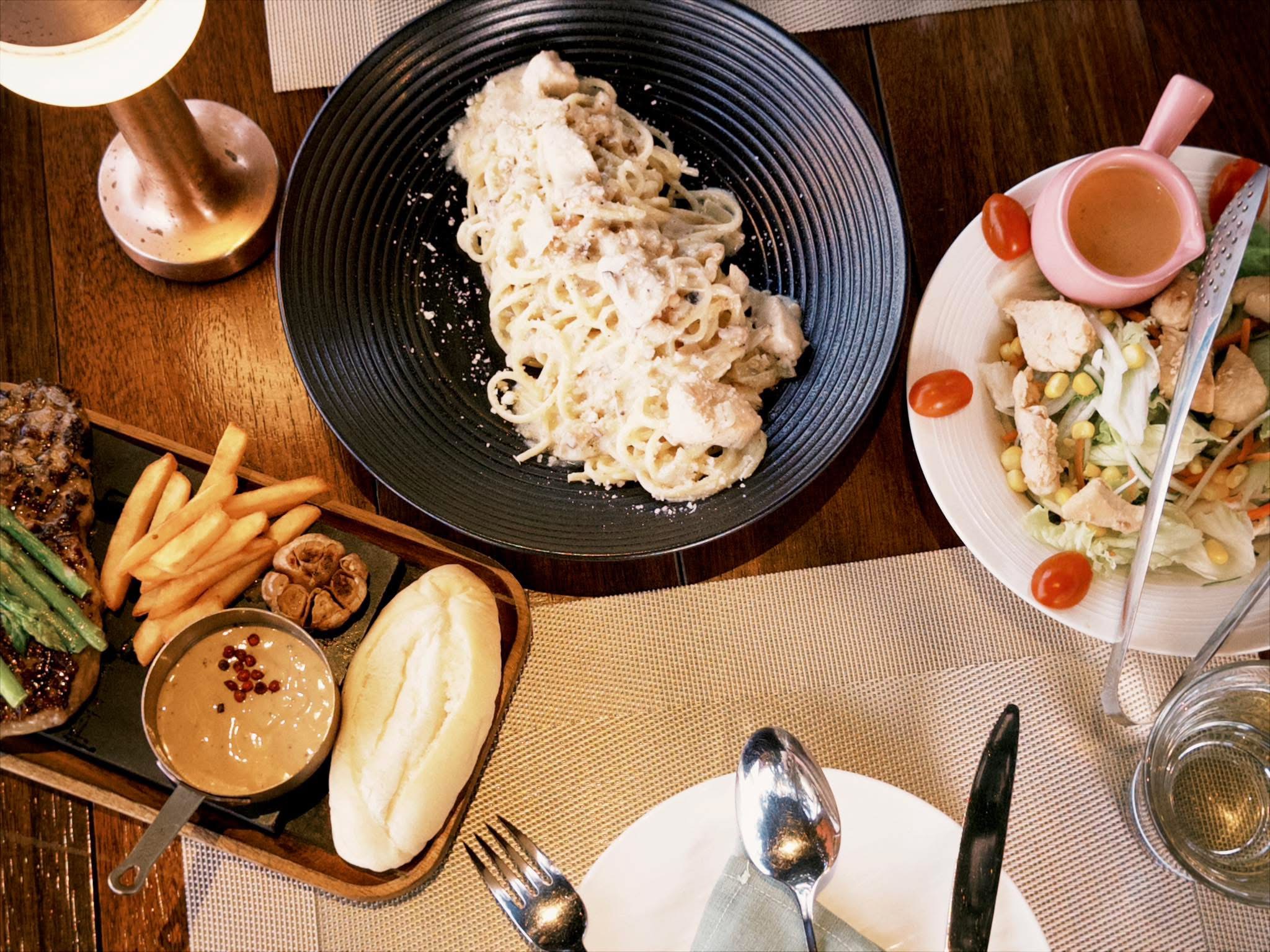 Bàn ăn Horizon với steak, pasta và salad dùng trong buổi tối